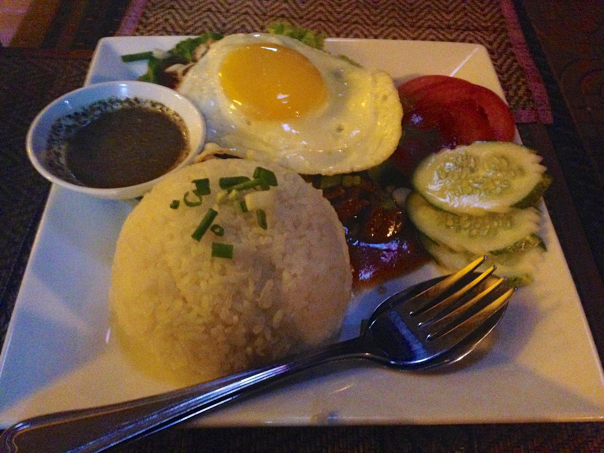 Beef lok lak served with rice, a fried egg, and dipping sauce