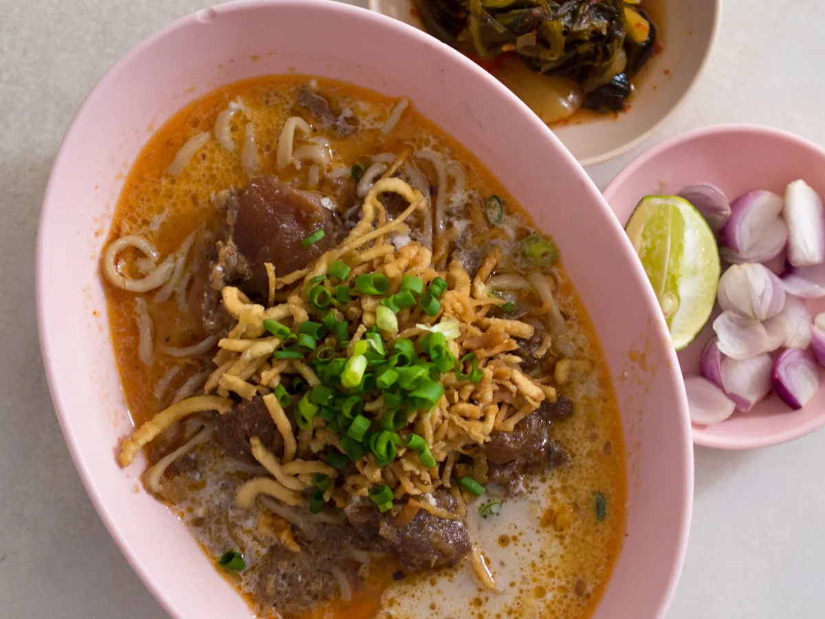 Khao soi curry noodles with lime, shallots, and pickled greens