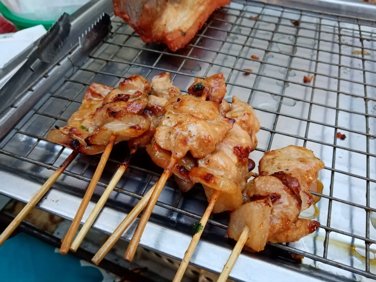 Moo ping grilled pork skewers on a street food grill